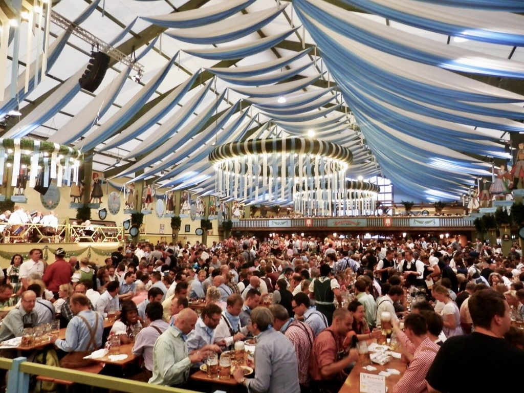 ミュンヘンのオクトーバーフェストのテント内でビールを飲む人々