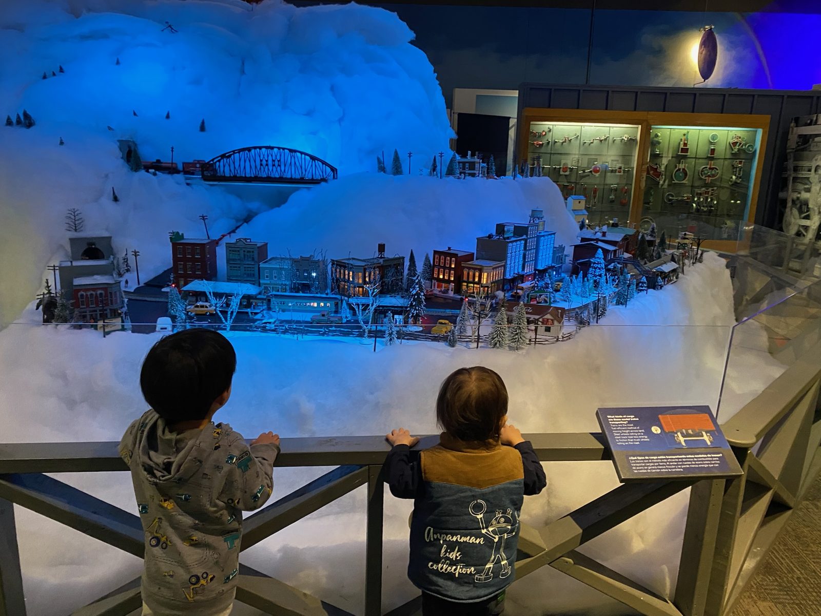 雪景色のジオラマを走る鉄道模型を見る子どもたち