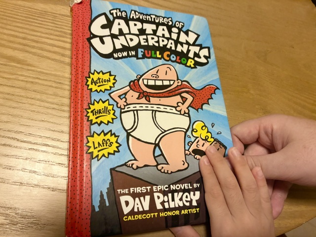 Captain Underpants（キャプテンアンダーパンツ）の本を親子で持つ様子。

