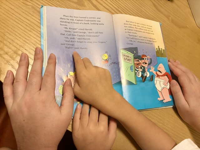 父と息子が一緒にCaptain Underpants（キャプテンアンダーパンツ）を読んでいる様子。